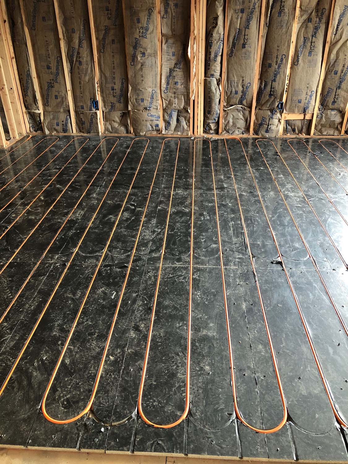 Copper radiant heat tubing laid in serpentine loops across a subfloor for radiant floor heating in Staten Island